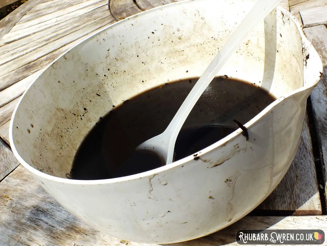 mixing bowl full of muddy water, with a spoon in.