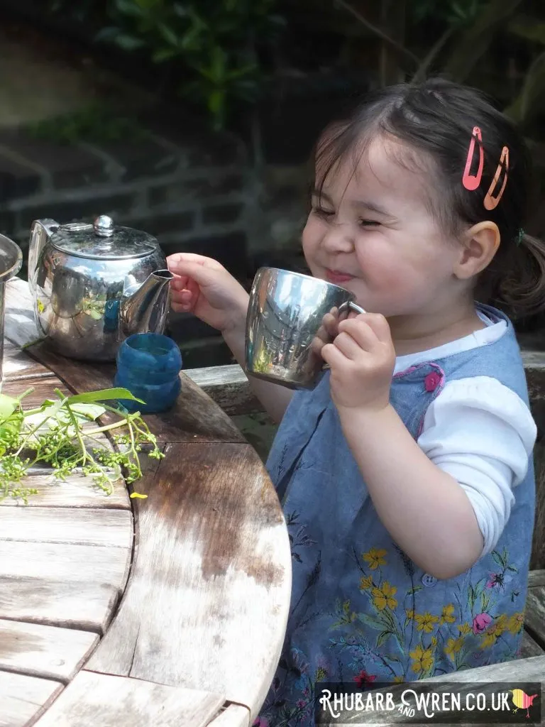 child drinking pretend tea in the garden.