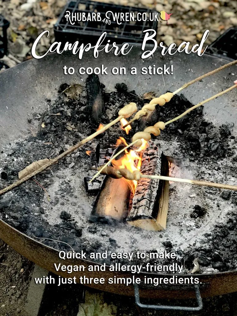 Cooking damper bread on sticks over a fire pit campfire