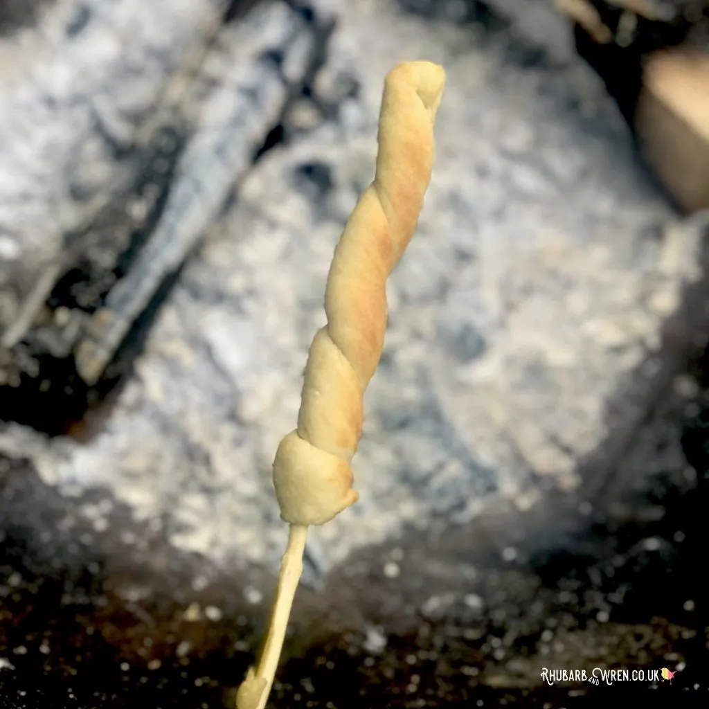 damper bread cooked on a stick over a campfire