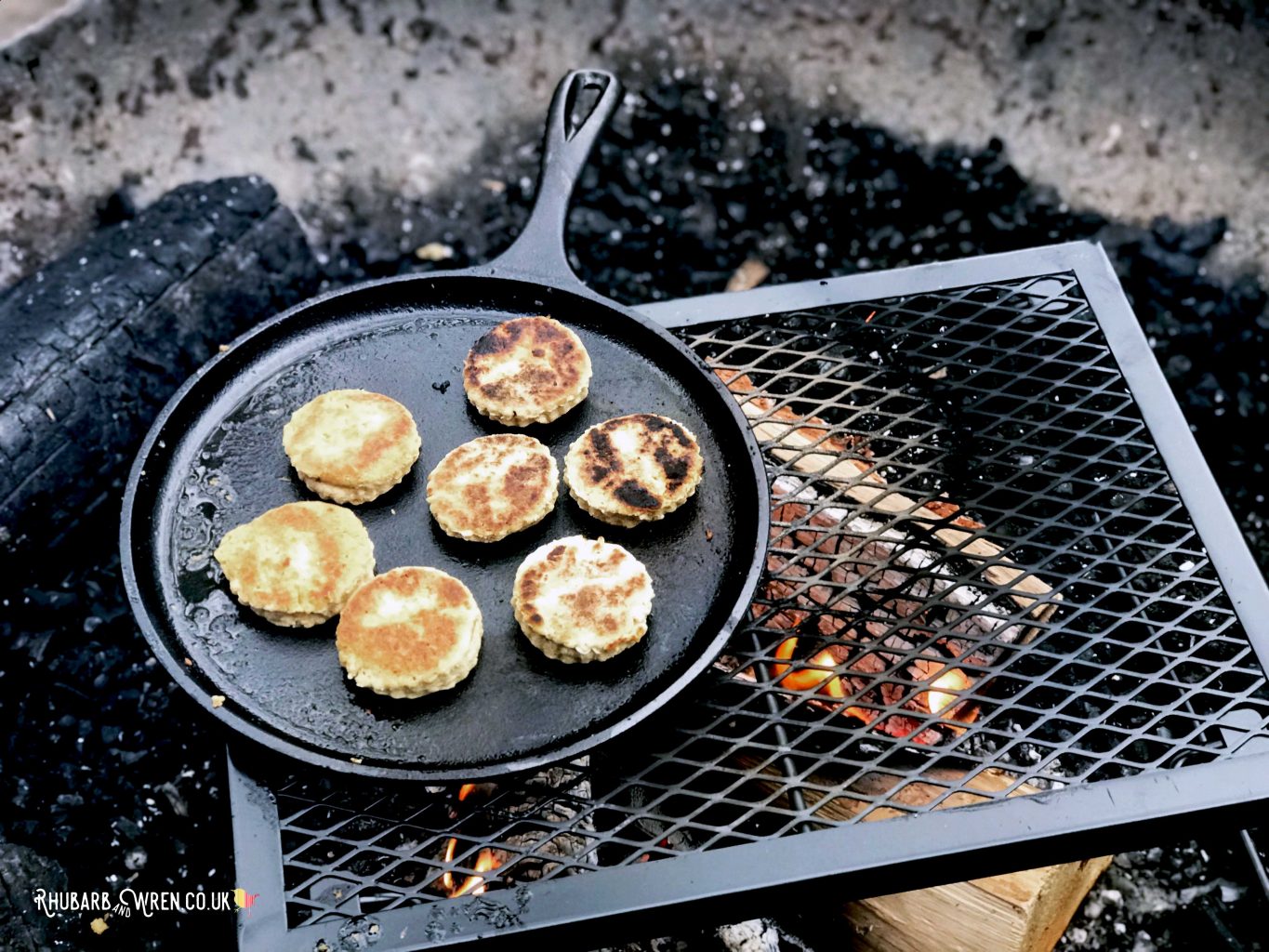 A cast iron pan full of Welsh cakes, cooking over a campfire