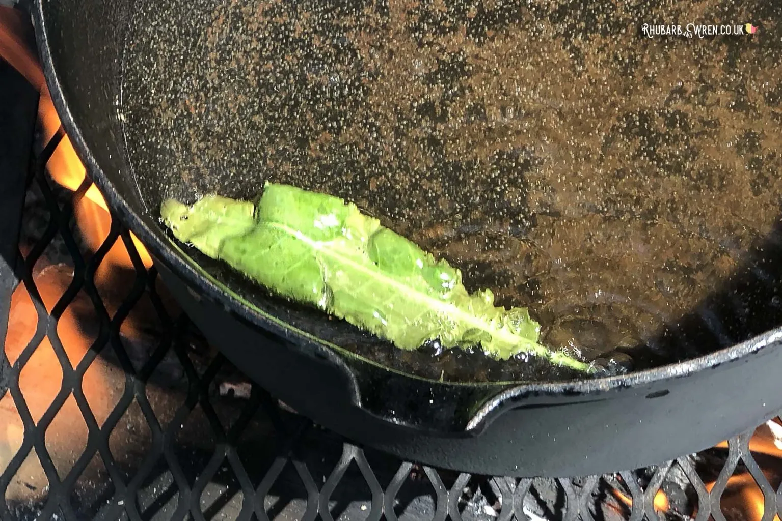 A dandelion leaf frying in oil to make dandelion crisps