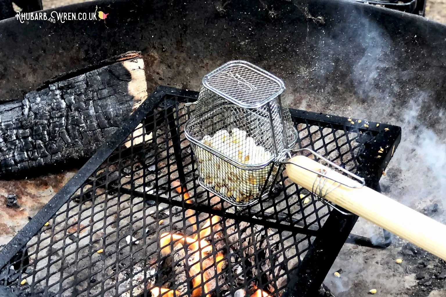 popped popcorn kernels in a DIY cage over a campfire