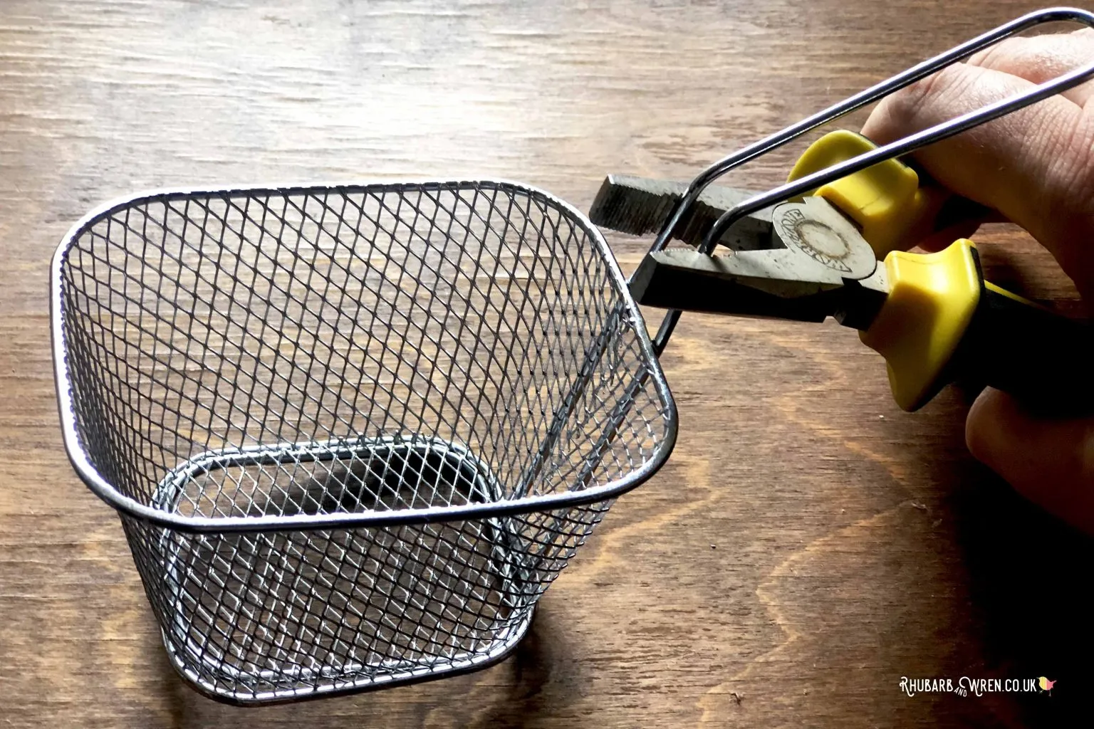 Pinching the handle of a frying basket to make it narrower.
